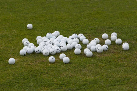 Assortment of white golf balls on the green grassの写真素材