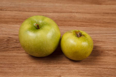 Two juicy green apples on a wooden tableの写真素材