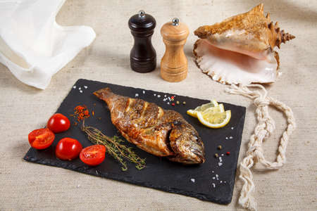 grilled dorado served with fresh cherry tomatoes on a slate plate-a gourmet dinner at the restaurantの写真素材