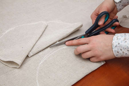 Woman's hands are cutting fabric with a tailors scissorsの写真素材