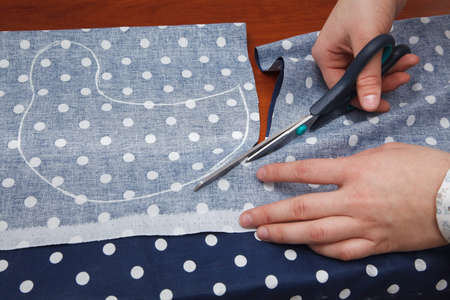 Woman's hands are cutting fabric with a tailors scissorsの写真素材