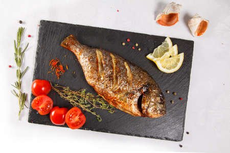grilled dorado served with fresh cherry tomatoes on a slate plate-a gourmet dinner at the restaurantの写真素材