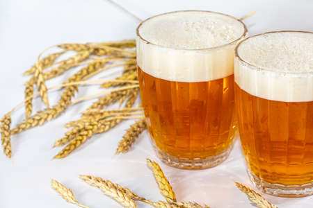 two mugs of fresh Beer with ears of barley isolated on the white backgroundの写真素材