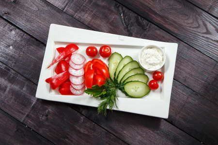 Platter of assorted fresh sliced vegetables with dip on the dark backgroundの写真素材
