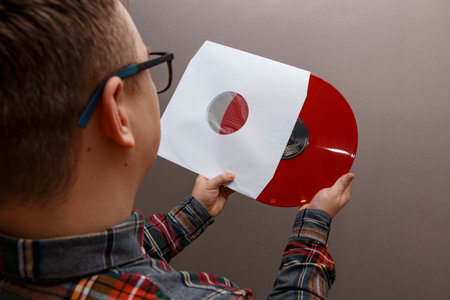 man in glasses takes out a red vinyl record from a paper envelopeの写真素材