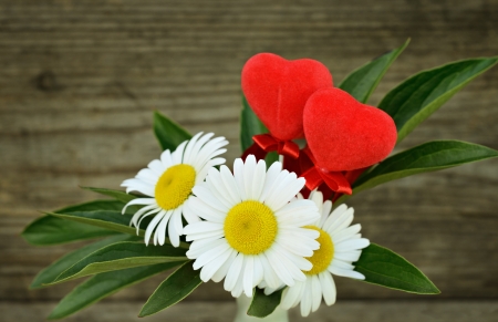 Bouquet with daisies and two red hearts on old wooden backgroundの写真素材