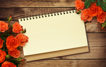 Notepad and roses on wooden backgroundの写真素材