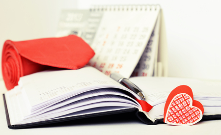 Pen, necktie and a heart on opened notebookの写真素材