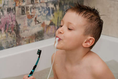 boy in the bathroom brushes his teeth spits foam
