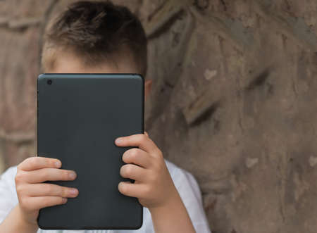 boy with tablet near school with a book online learningの写真素材