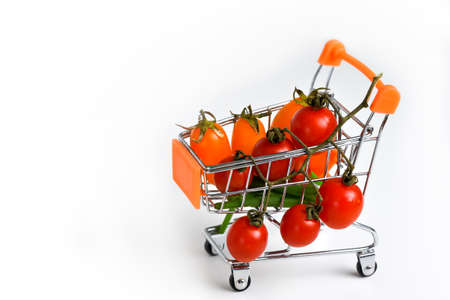 shop wheelchair with cherry tomatoes, shop purchases close-up, decorated top view on white background isolate. Cherry tomatoes in a metal shopping cart on a white background, close up, macro photography. High quality photoの写真素材