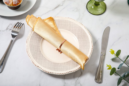 Elegant table setting with golden napkin and cutleryの写真素材