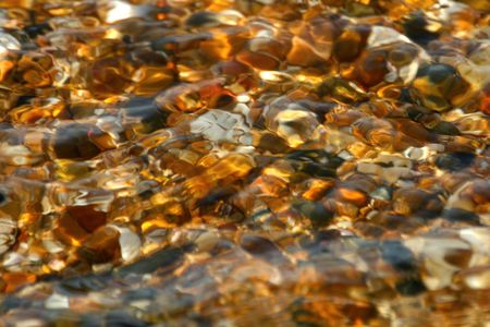 Smooth clear water flowing over colored pebbles and rock in a creekの写真素材