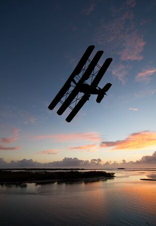 Silhouette image of World War One Triplane flying during a nice sunset or sunrise.
