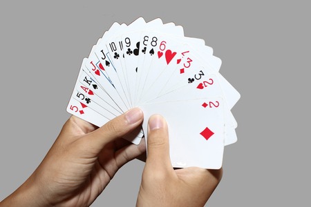 Playing cards in hand isolated on gray background