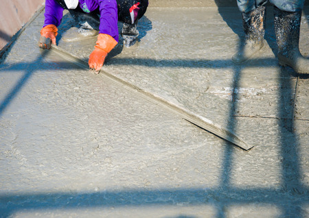 Worker pouring cement in construction siteの写真素材