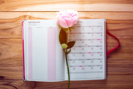 Gigt box with calendar book , rose flower and white ribbon. Valentines day simbols on a wood backgroundの写真素材