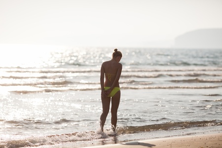 Rear view on a single lady going into the seaの写真素材