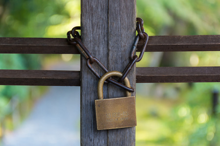 Locked gate with vintage lockpad and rusty chain in the garden located in Kyotoの写真素材