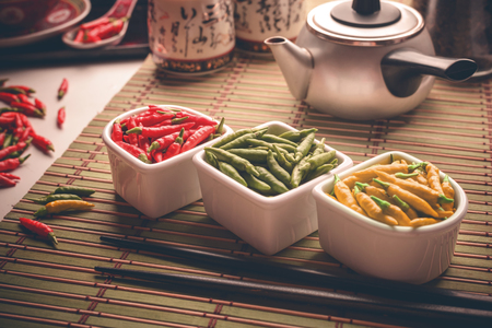 Red, green and yellow peppers on an oriental style table. Depth of field with focus on center of the image.の写真素材