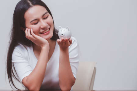 Piggy bank in hand of smiling woman, save money and management financial concept.の写真素材