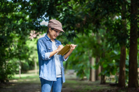 Botanists are standing and taking notes for research in the forest park.の写真素材