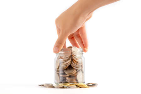 The woman hand is picking a glass bottle with full coin in the middle of the pile of coins isolated...