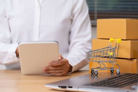 Female seller is checking the number of orders for her products that have been ordered using the tablet. Online Shopping and E-commerce concept.の写真素材