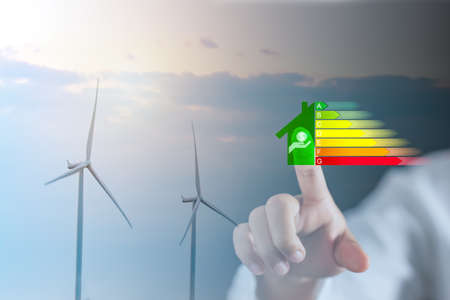 Energy efficiency and green energy concept, woman hand touch energy efficiency symbols with wind turbines.の写真素材