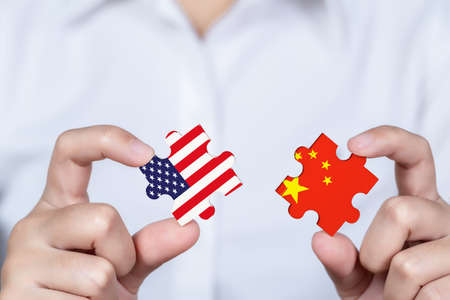 Hand holding USA and China jigsaw puzzle piece, Symbolic concept about trade war between USA and...