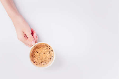 Coffee latte in holding hand female on white background. Close up. Top view.