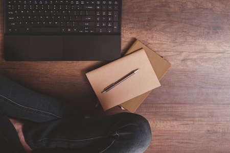 Top view of pen on notebook with laptop and woman's lap on wooden floor.の写真素材