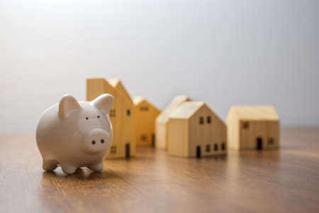 Piggy bank and wooden house on wooden desk,  Save money and buy house concept.の写真素材