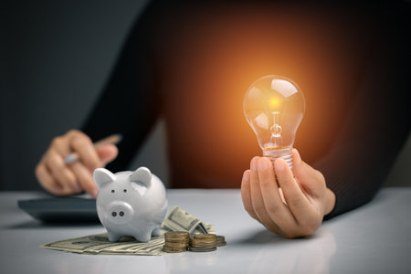Hand holding a light bulb with piggy bank, dollar bill, coins stack. Money management for the future, Personal Financial Management and Design concept.の写真素材