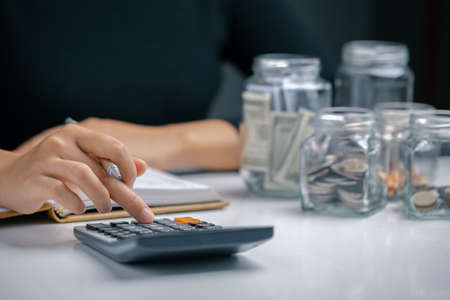 Woman presses a calculator and writing make note with business stuff, Money management for the future, Personal Financial Management and Design concept.の写真素材