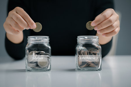 Woman hand putting coin in the glass jar for saving and emergency, Saving for Emergency concept.の写真素材