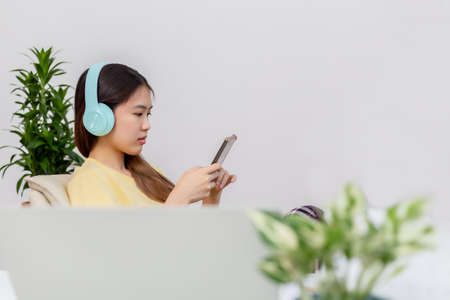 Asian woman happy cute beautiful using phone for listening to music with earphones.の写真素材