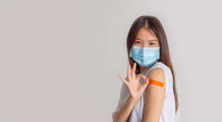 Asian woman wearing face mask with a smile on his face showing his vaccinated arm. vaccination,...