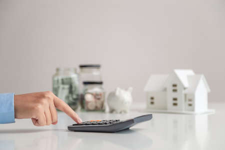 Woman presses a calculator to calculate the value during rental or purchase. Saving money for house, Buying, Renting home, Purchase housing, Real estate concept.の写真素材