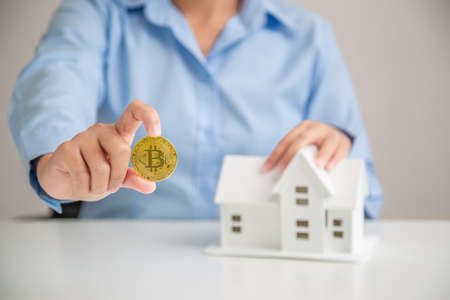 Woman hand holding bitcoin for buying savings home, Investment home bitcoin. Home buying savings concept.の写真素材
