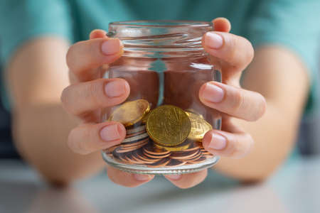 Hand holding a glass jar with money for saving money, wealth, business, investment, retirement, Concept financial for the future.の写真素材