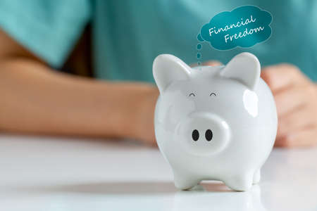 Happy smiley face piggy bank with text label "financial freedom"  Saving money for financial independence or financial freedom concept.の写真素材