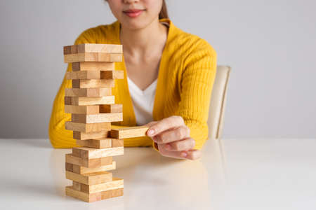 Asian woman placing and pulling wood block on the wooden block tower game.の写真素材