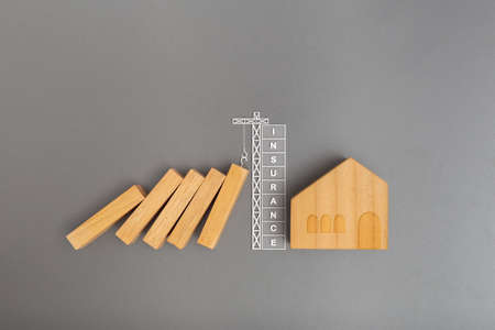 Derrick is lifting wooden blocks, Housing crisis and home insurance. Real estate, Property insurance and security.の写真素材
