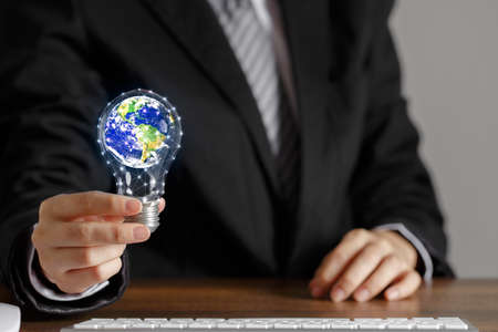 Businessman hand hold light bulb with globe inside. Concept of doing business with care for...