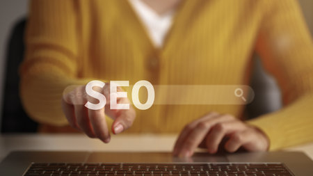 Woman hand touching letters "SEO" through search bar. Concept of ranking search results to move them to the top of the search results for users.の写真素材