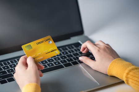 A woman holds a credit card and pays for an online purchase.の写真素材