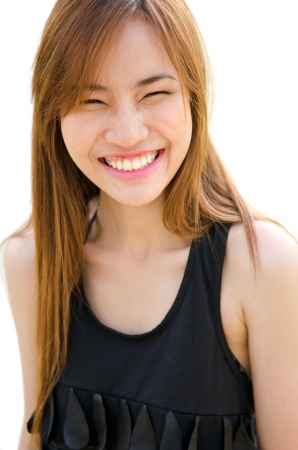 A cute young Asian giggling with eyes closed over white background の写真素材