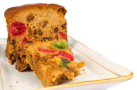 delicious sliced fruit cake with mixed fruit and cherries on white plate isolated on white backgroundの写真素材