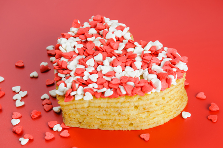 Pile of pancakes in the shape of a heart on red background with little sugar heartsの写真素材